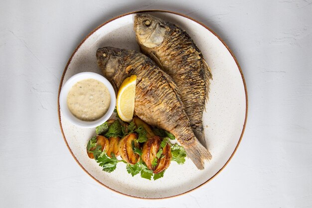 Fish as food and white plate with fried fish with potatoes a\
white plate is prepared as food