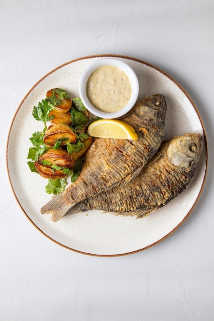 Fish as food and white plate with fried fish with potatoes a\
white plate is prepared as food