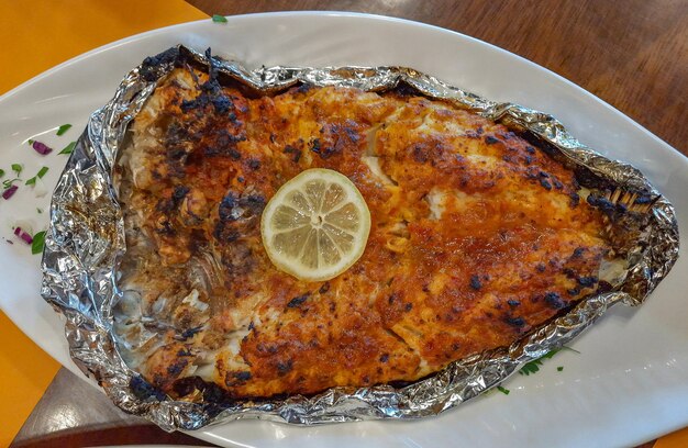 Fish baked in foil on table with lemon top view