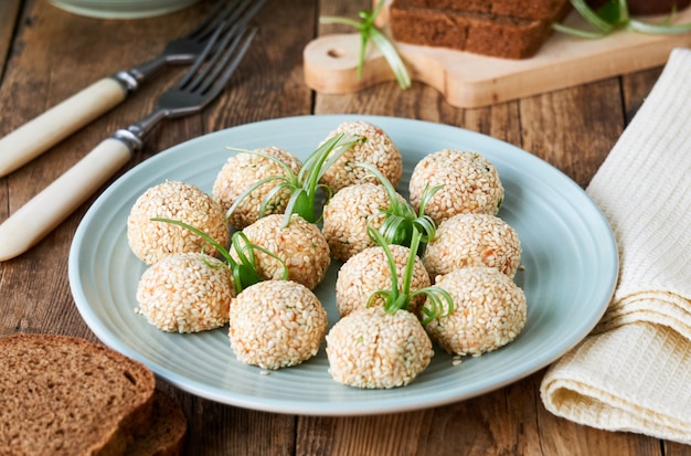 Fish balls with vegetables and sesame seeds on a blue plate