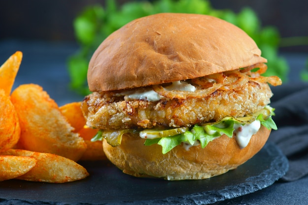 Foto hamburger di pesce con cipolle fritte e salsa