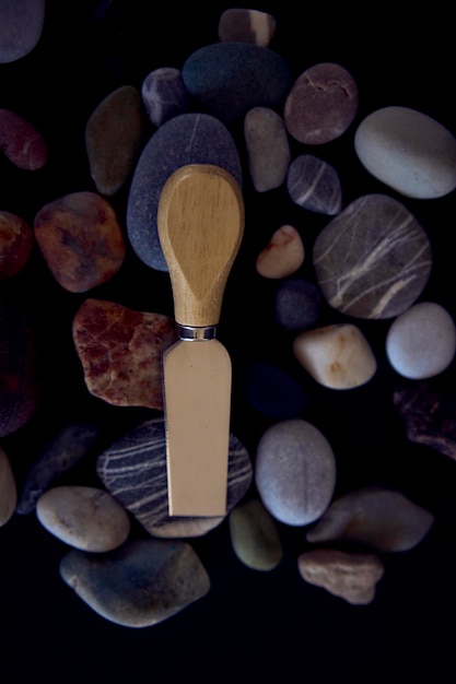 Photo fish and cheese knife with a wooden handle on a black background with sea pebbles