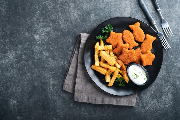 Chips di pesce fast food britannico bastoncini di pesce con patatine fritte su piastra nera su sfondo nero della tavola cibo di strada autentico britannico tradizionale o cibo da asporto mock up con spazio per il testo