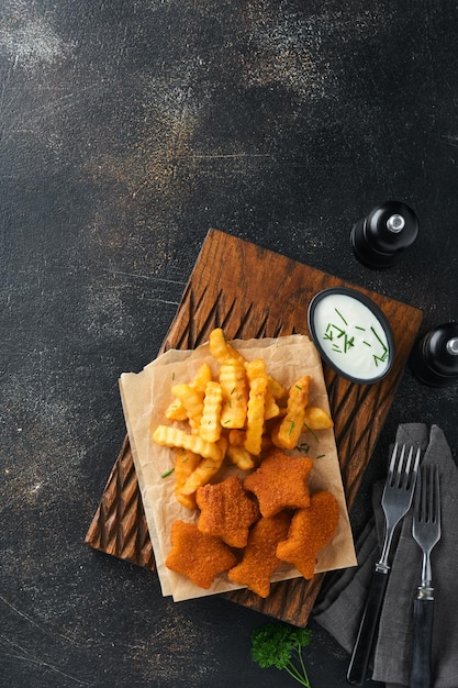 Fish and Chips british fast food Fish Sticks with french fries set on rustic board on dark old concrete background Traditional British authentic street food or takeaway food Mock up Top view