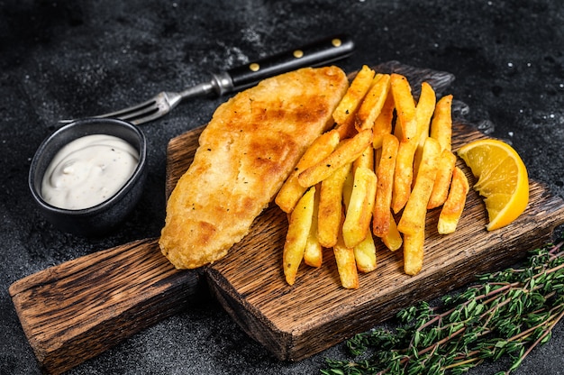 Fish and chips dish with french fries on wooden board