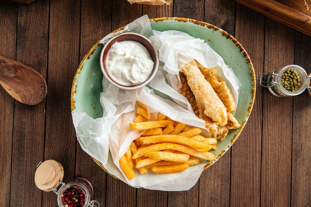 Piatto di fish and chips con patate fritte e salsa cremosa