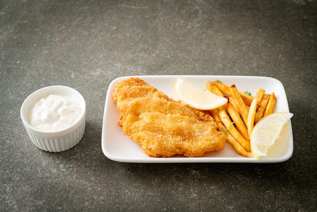 fish and chips - fried fish fillet with potatoes chips and lemon on white plate