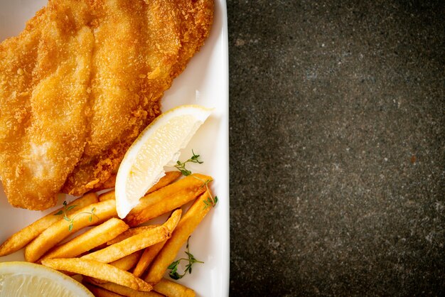 fish and chips - fried fish fillet with potatoes chips and lemon on white plate