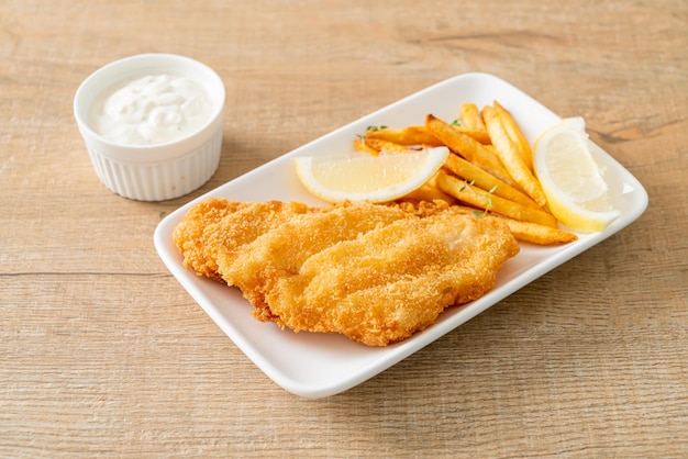 fish and chips - fried fish fillet with potatoes chips and lemon on white plate