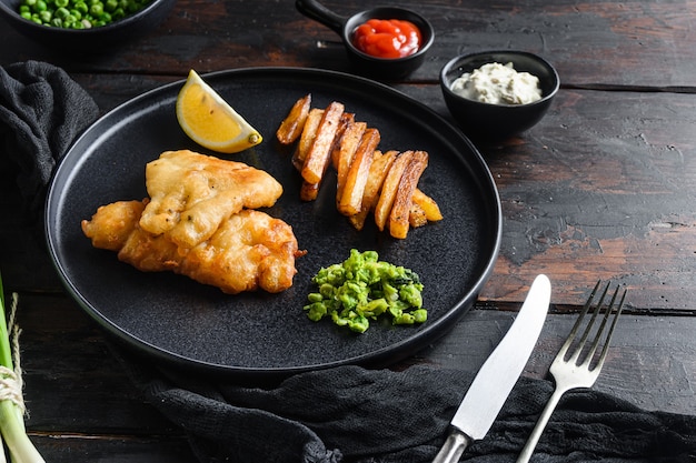 Fish chips with dip and lemon black plate with british traditional cusine food