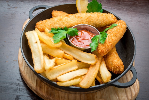 Pesce e patatine fritte sulla tavola di legno, alimento saporito.