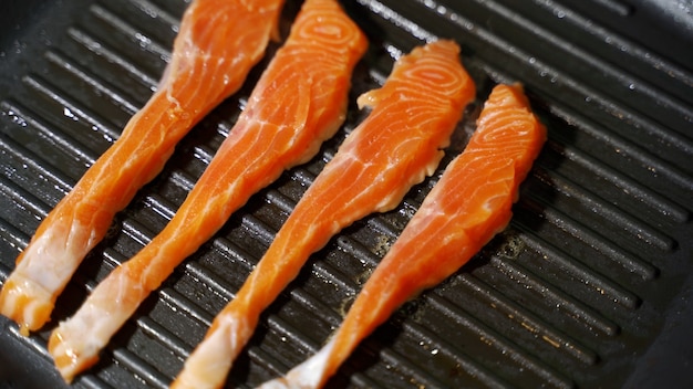 Fish cooking recipe piece of salmon or trout fillet frying on grilled pan