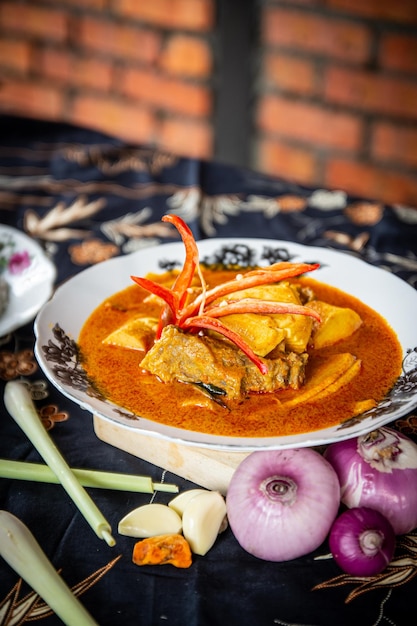 Fish curry traditional malaysian fish curry kerala special dish\
using coconut arranged in a white