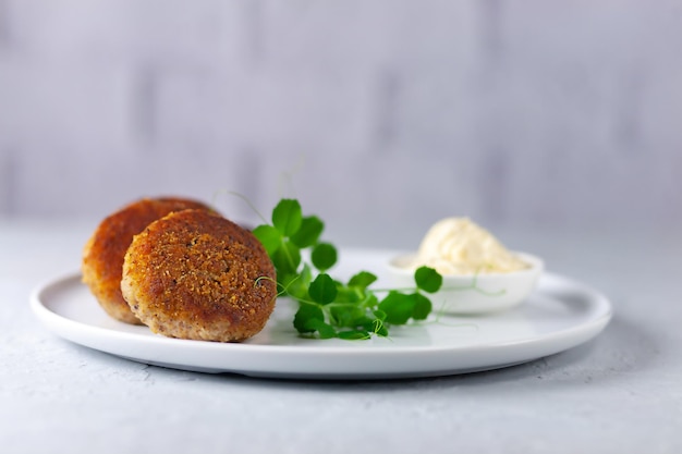 Fish cutlets with mayonnaise on a white plate