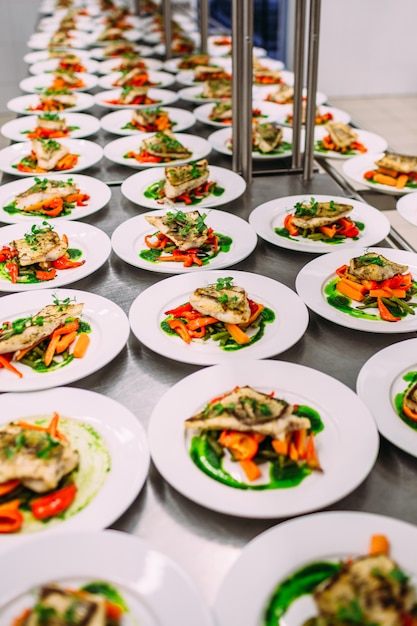 Fish dish with vegetables for catering. Lots of plates.