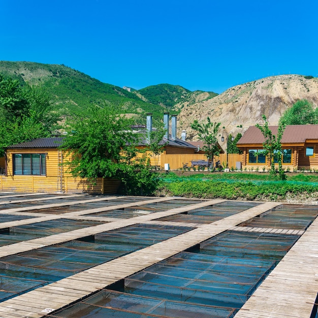 Fish farm in a mountain valley with aquaculture cages and wooden buildings