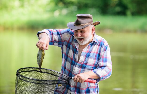 Fish farming pisciculture raising fish commercially fisherman\
alone stand in river water man senior bearded fisherman fisherman\
fishing equipment hobby sport activity pensioner leisure