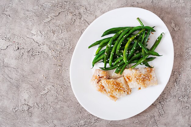 Fish fillet served with soy sauce and green beans in white plate. Asian food. Top view. Flat lay