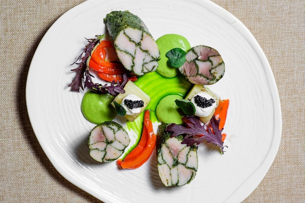 Fish fillet with raw vegetables and sauce in a white plate on the tabletop view