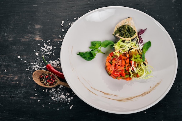 Foto filetto di pesce con salsa di spinaci e verdure al vapore vista dall'alto su sfondo di legno spazio di copia