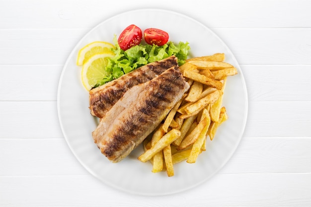 Fish and french fries on white plate