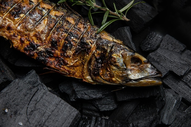 A fish on a grill with a rosemary sprig on it