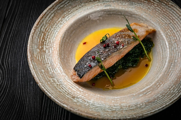 Fish grilled on a plate on a dark wooden table