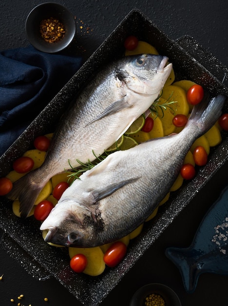 写真 焼く準備ができたポテトとトマトを天板に乗せた魚