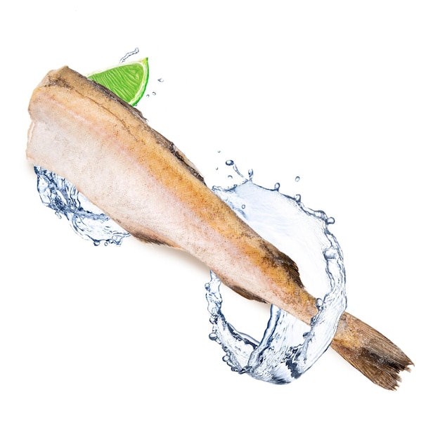 A fish is being poured into a glass with a lime slice in it.