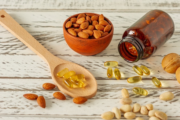 Fish oil capsules and assortment of nuts on wooden background and texture, vitamin D, omega supplement, selective focus.