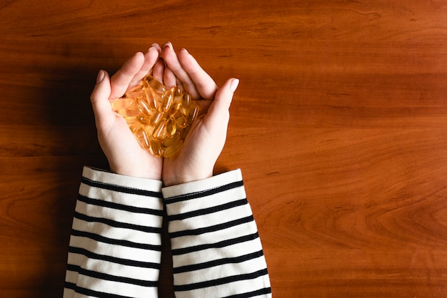 Capsule di olio di pesce sulle mani femminili