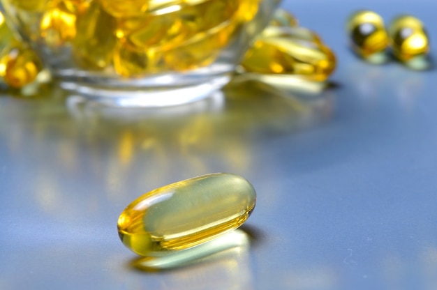 Fish oil capsules on a glass plate. A lot of vitamin omega 3. Close-up.