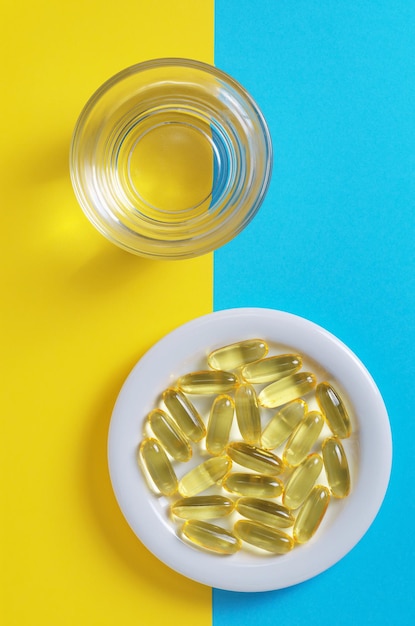 Fish oil capsules and glass of water