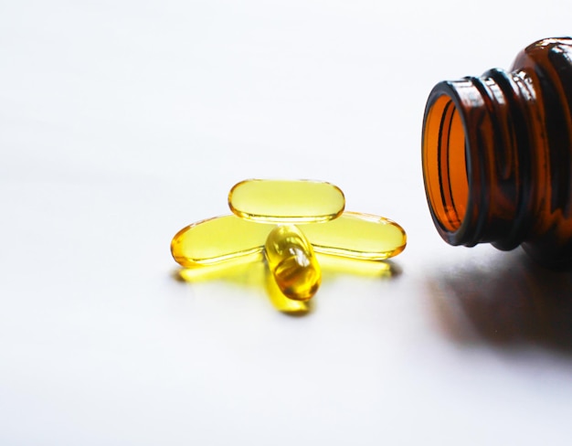 Photo fish oil capsules on white background and texture fish oil capsules and container selective focus