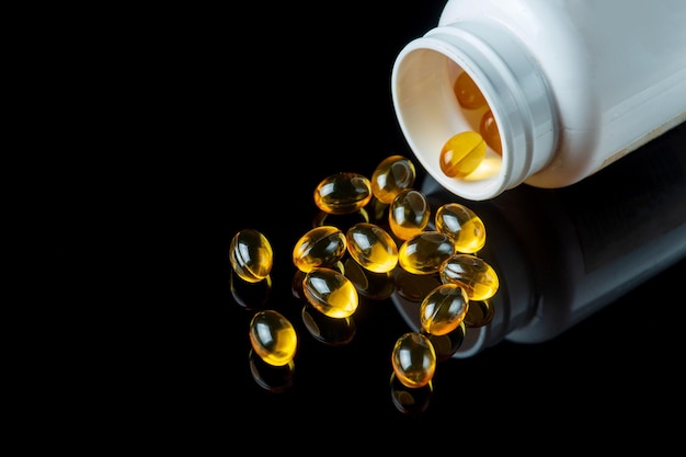 Fish oil capsules in white bottle isolated on black background. Healthy Omega 3 Supplement.