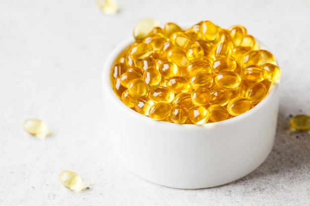 Fish oil capsules in white bowl on gray background