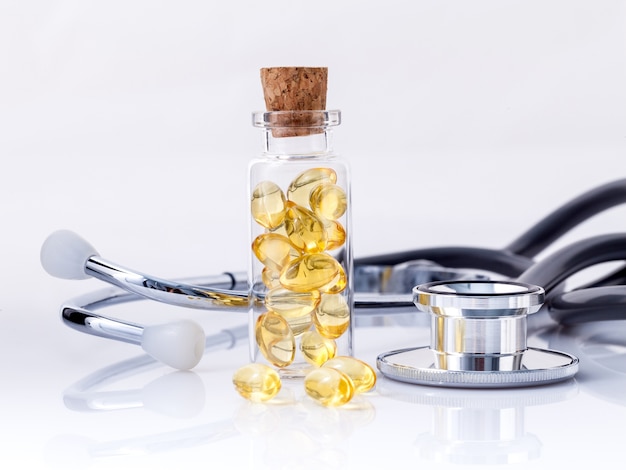 Fish oil capsules with stethoscope isolate on white background.