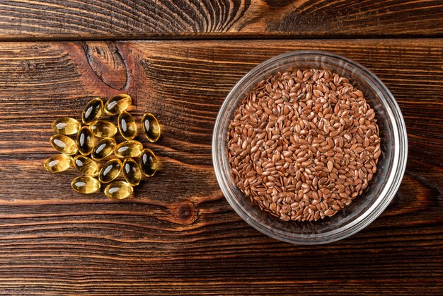 Fish oil and flax seeds on dark wooden table.