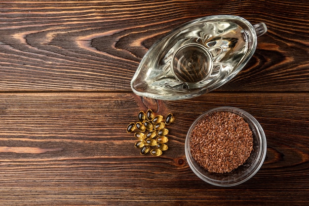 Fish oil and flax seeds on dark wooden table.