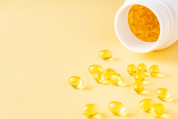 Capsule di supplemento di gel morbido di olio di pesce fonte di omega 3 e vitamine ae su sfondo giallo yellow