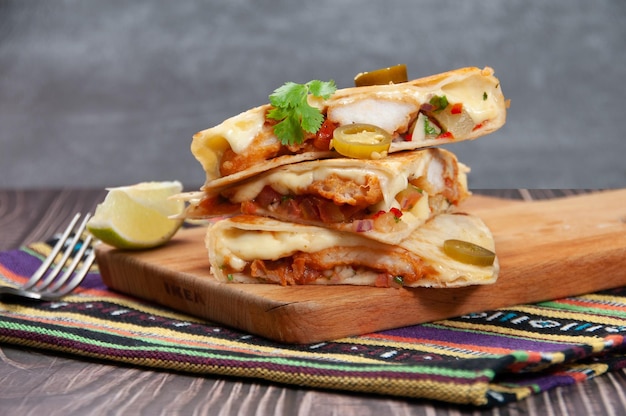 Fish quesadillas isolated on wooden board and mat side view of\
fastfood on wooden background