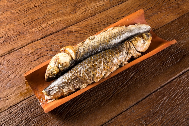 рыба, запеченная на плитке на старом деревянном столе