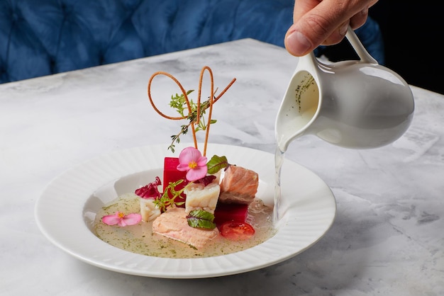 Fish soup decorated with flowers in which broth is poured