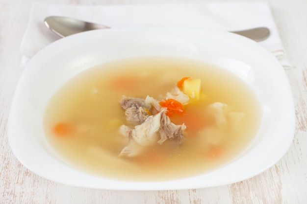 Fish soup in white plate with spoon