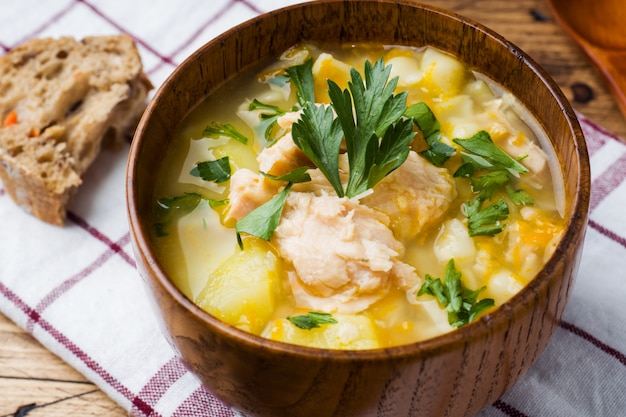 Fish soup in a wooden bowl with fresh herbs.