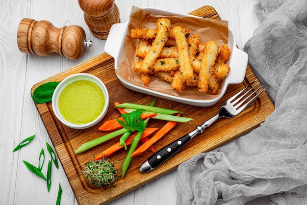 Fish sticks with fresh vegetables on a wooden board