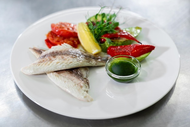 Fish and vegetables on a plate in a kitchen restaurant