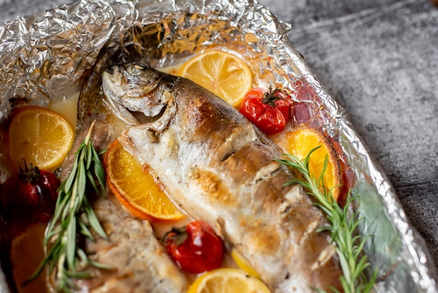 A fish with oranges and rosemary on it