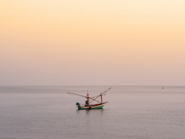 Fisher boat floating on the sea with golden sky in the morning