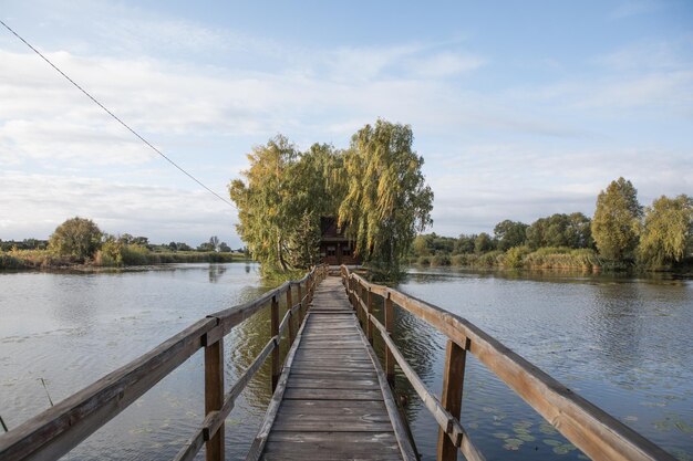 湖ウクライナ ジトームィル地域の真ん中に木製の橋とフィッシャーまたはハンターの家